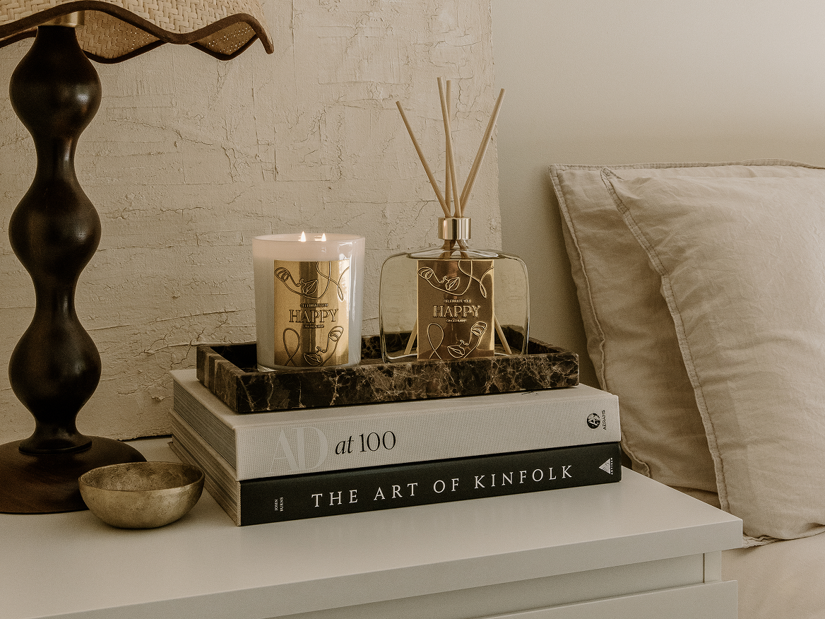 GINGER&ME Mindfulness candle and diffuser styled on a bedside table on top of a stack of books