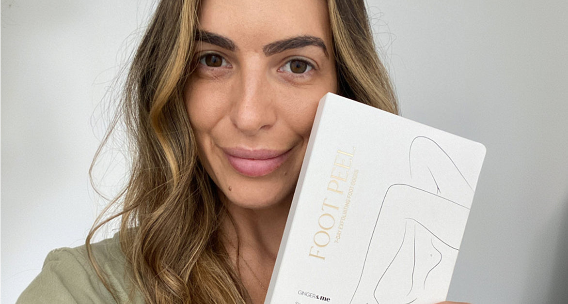 GINGER&ME content creator holding a GINGER&ME Foot Peel 7-Day Exfoliating Foot Socks box up beside her face.